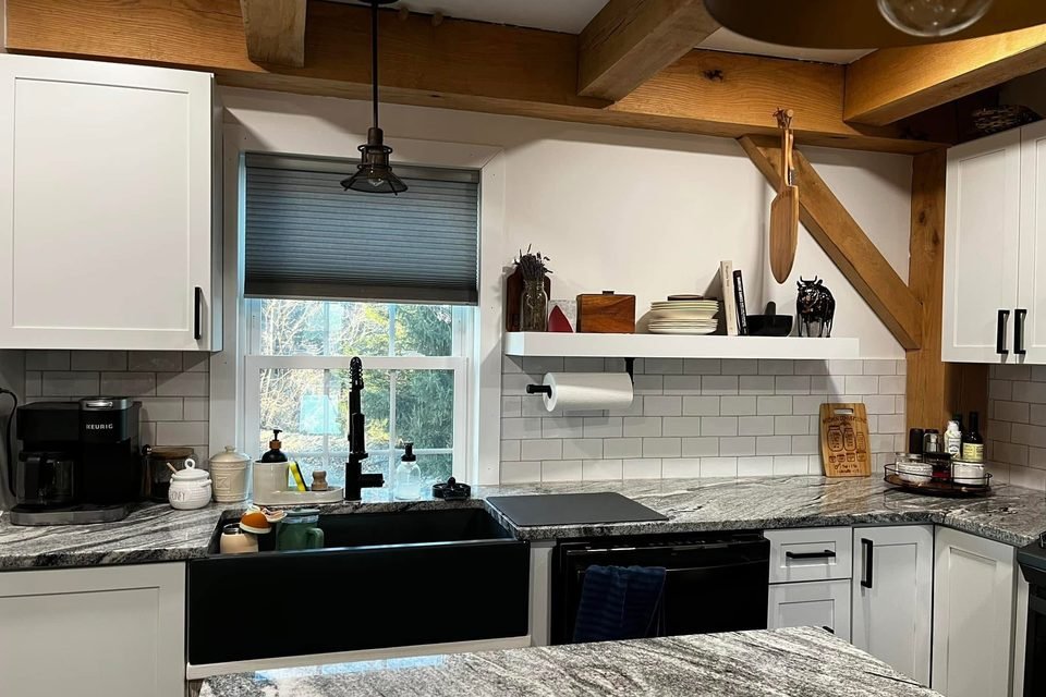 Kitchen sink, countertops and tile backsplash under wood beams