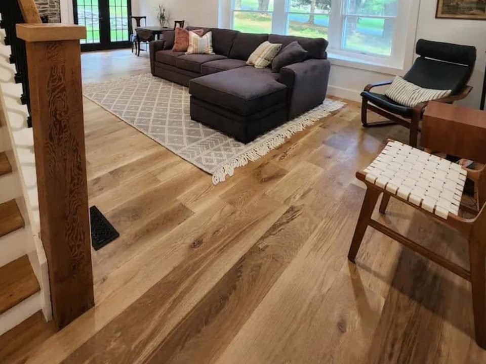 Open living room with wood floors, a staircase and exposed beams